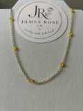 A delicate gold chain necklace with small yellow bead accents, displayed on a white jewelry stand with a circular James Rose Co. brand card behind it.